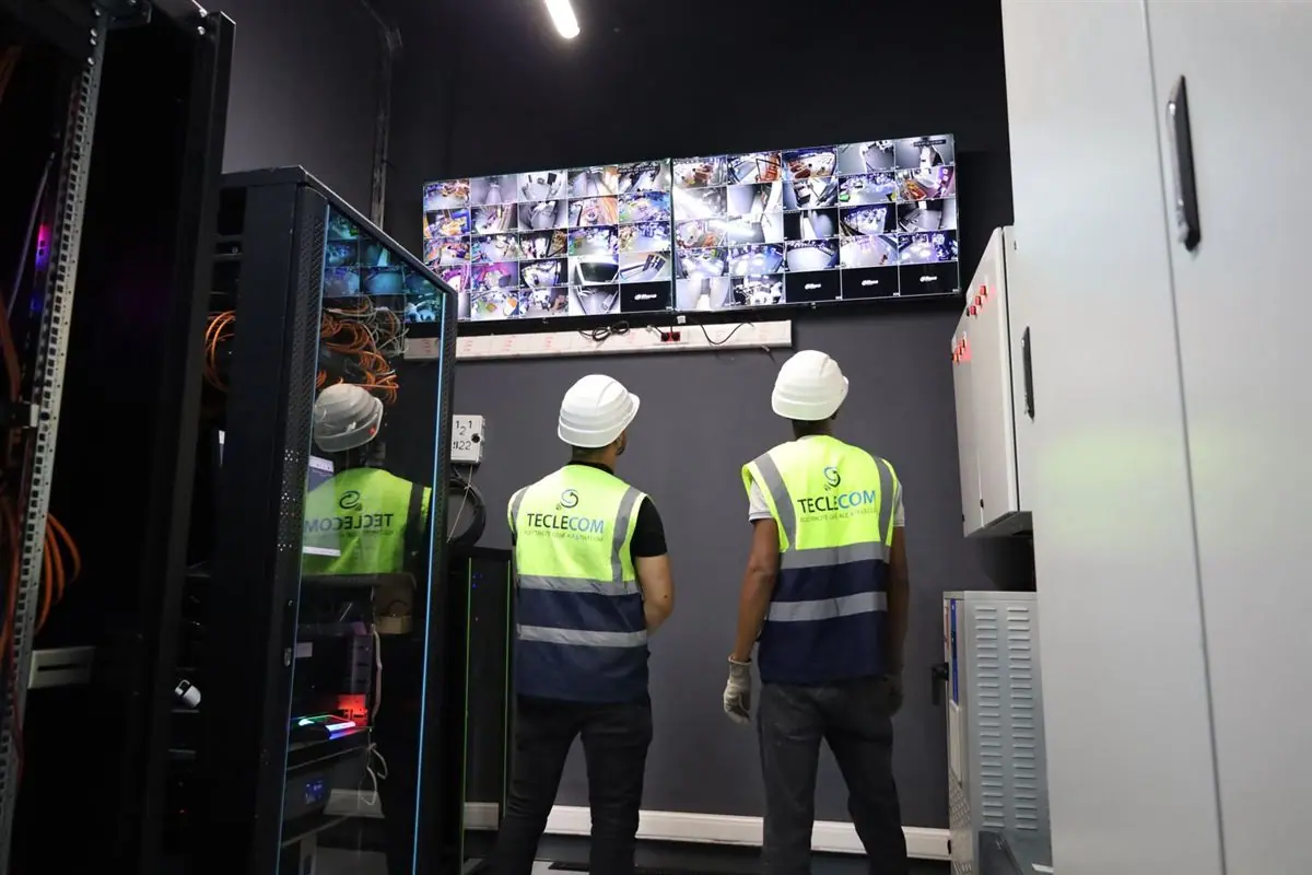 Techniciens Teclecom devant une baie réseau et un mur d’écrans